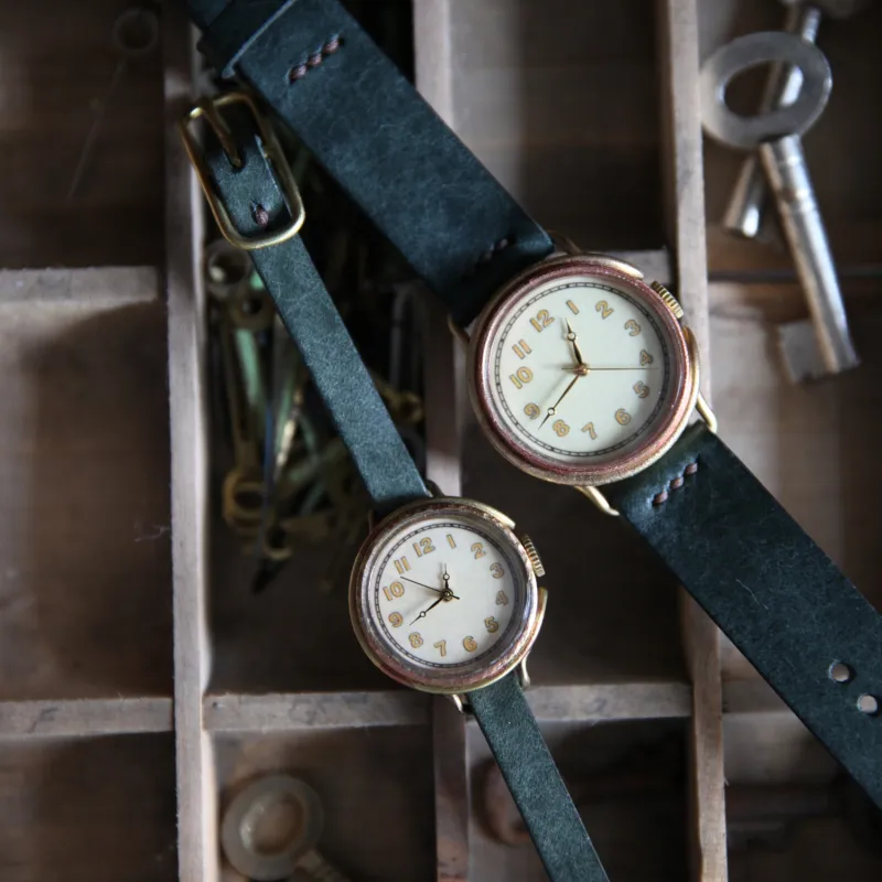 大小同じデザインの腕時計は、ペアウォッチとしてお勧めです。グリーンのベルトはコーディネートのアクセントになります。