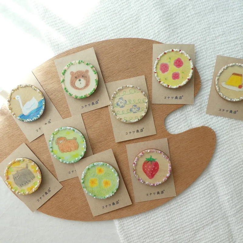 木のコインのブローチ。おうちで使うこども通貨用に用意した木片にお絵描きしてみたのがきっかけでできました。