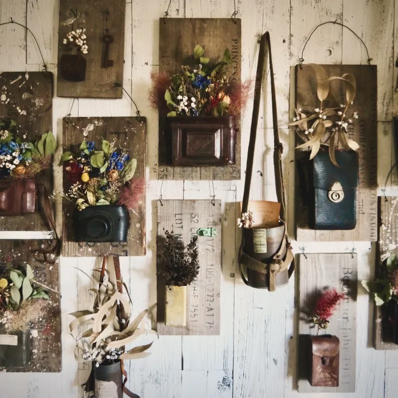古いカメラケースなどの古物とドライフラワーの融合