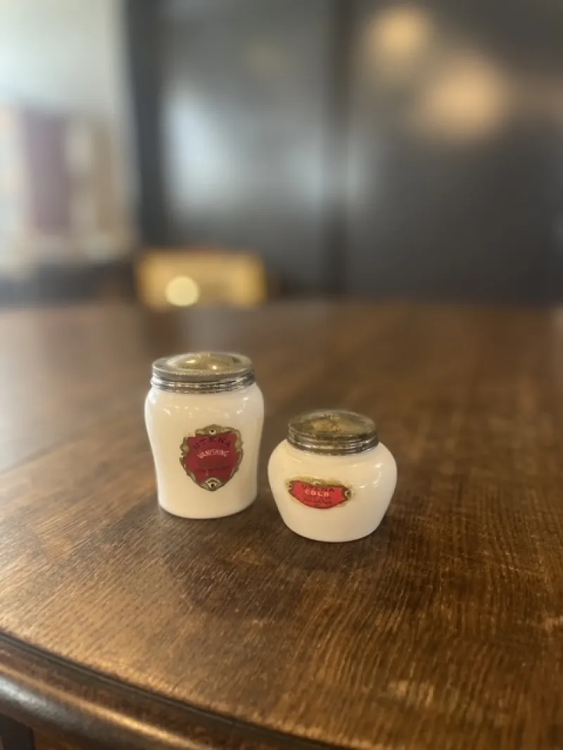 乳白色ガラスの化粧品瓶。赤いラベルと金属蓋が上品な雰囲気を醸し出しています。