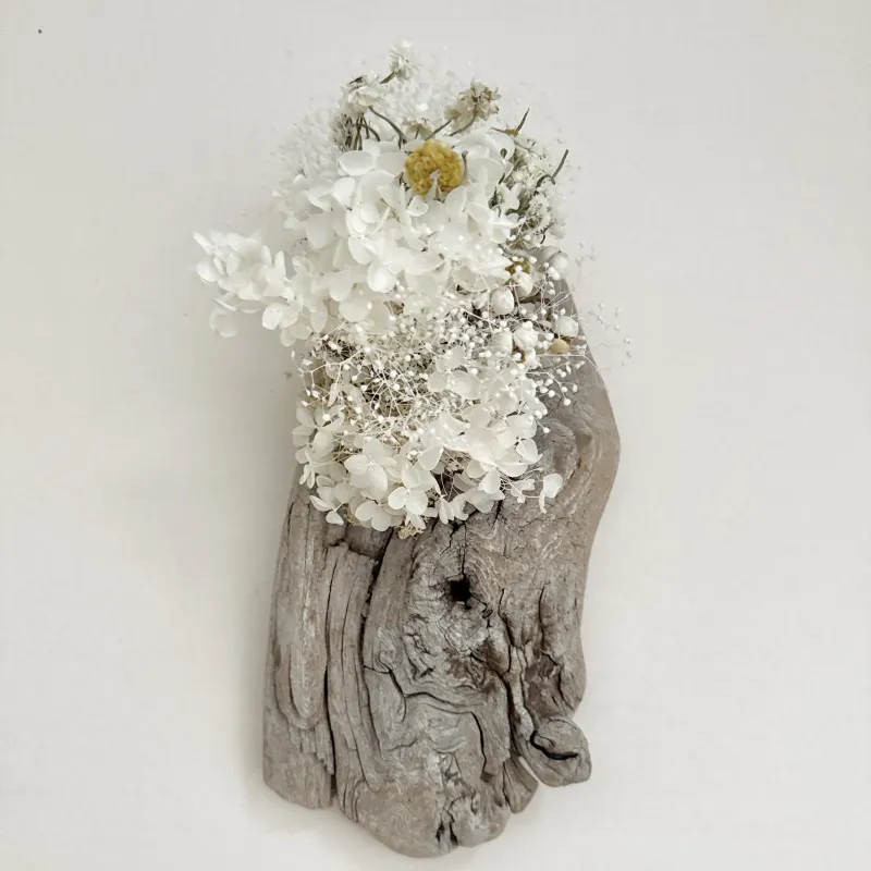 長い時を刻んで風化した流木に、白を基調とした様々お花を宿した壁飾りです。