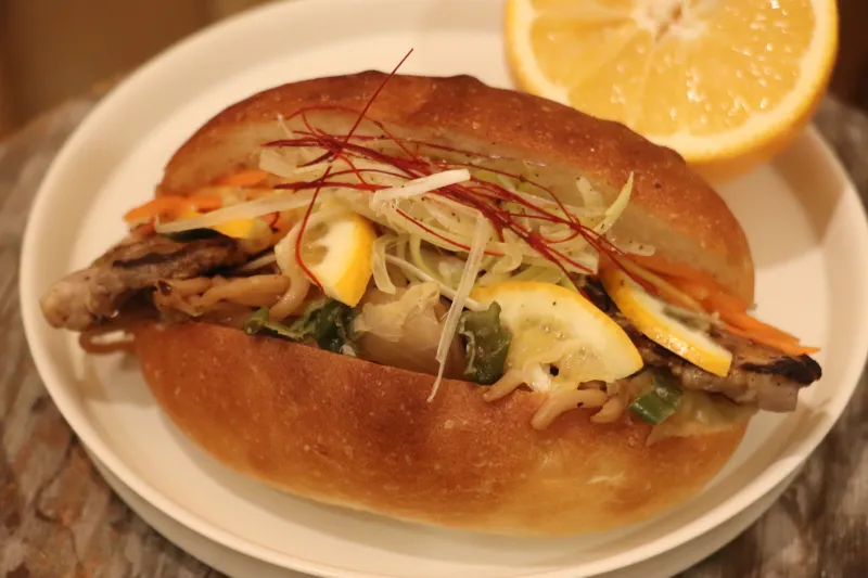 栃木県産小麦・イワイノダイチを使用した麺を自家製のねぎ豚と塩焼きそばにし、贅沢にはさみました。トッピングに宇都宮産の宮レモンを使用しています。
