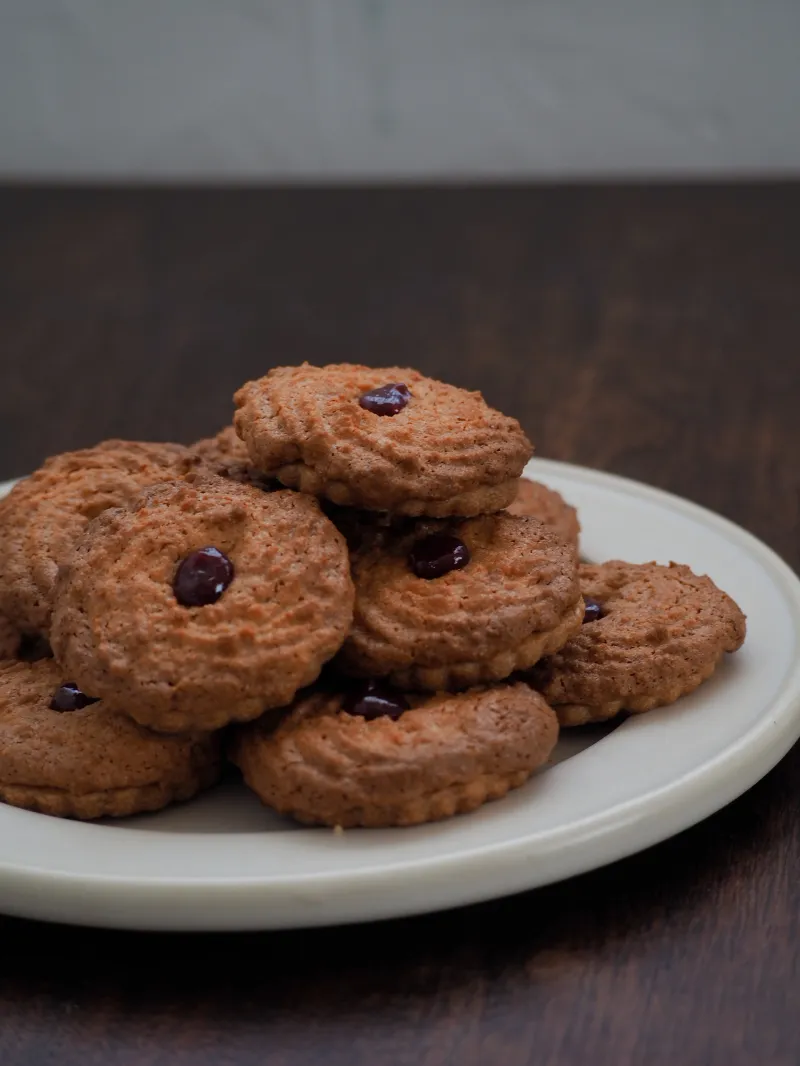 ドイツ伝統菓子「オクセンアウゲン」。食感の異なる2層のクッキー生地を重ね、中央にはラズベリージャムを飾ったおやつ