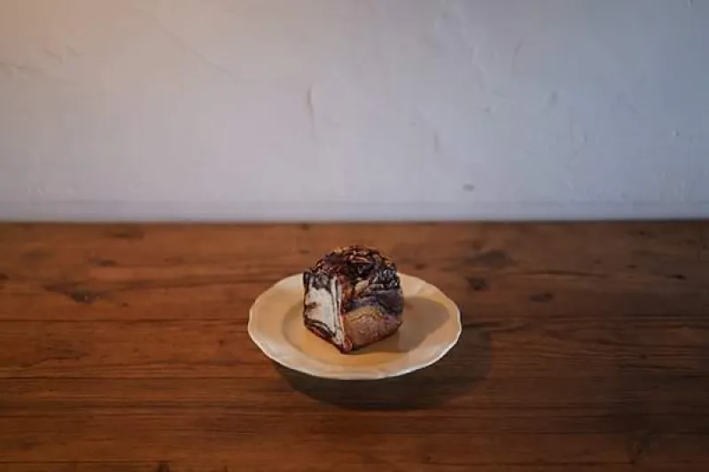 「チョコブレッド」上にナッツをトッピングした、チョコペーストを巻いた食パン。