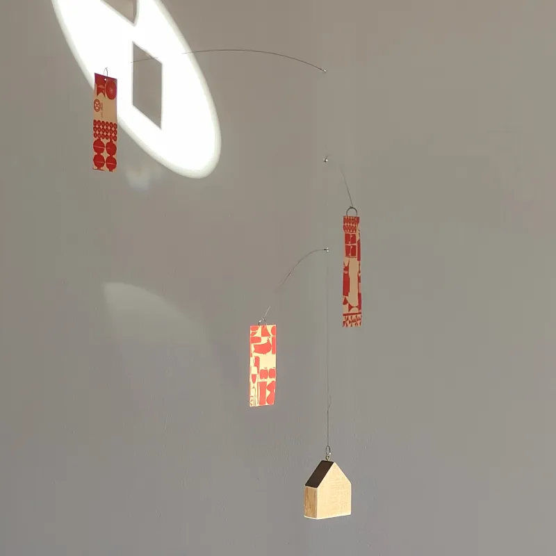 古紙を使ったオーナメントと、家の形の木のおもりでできたモビール。やさしく揺れる動きでお部屋に癒しをプラスできます。